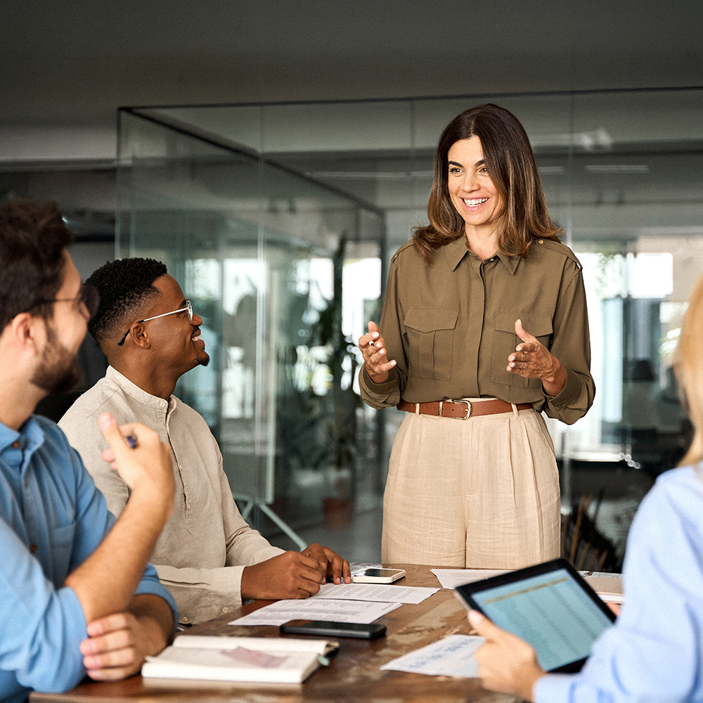 Happy middle aged business woman leader working with diverse team at meeting.