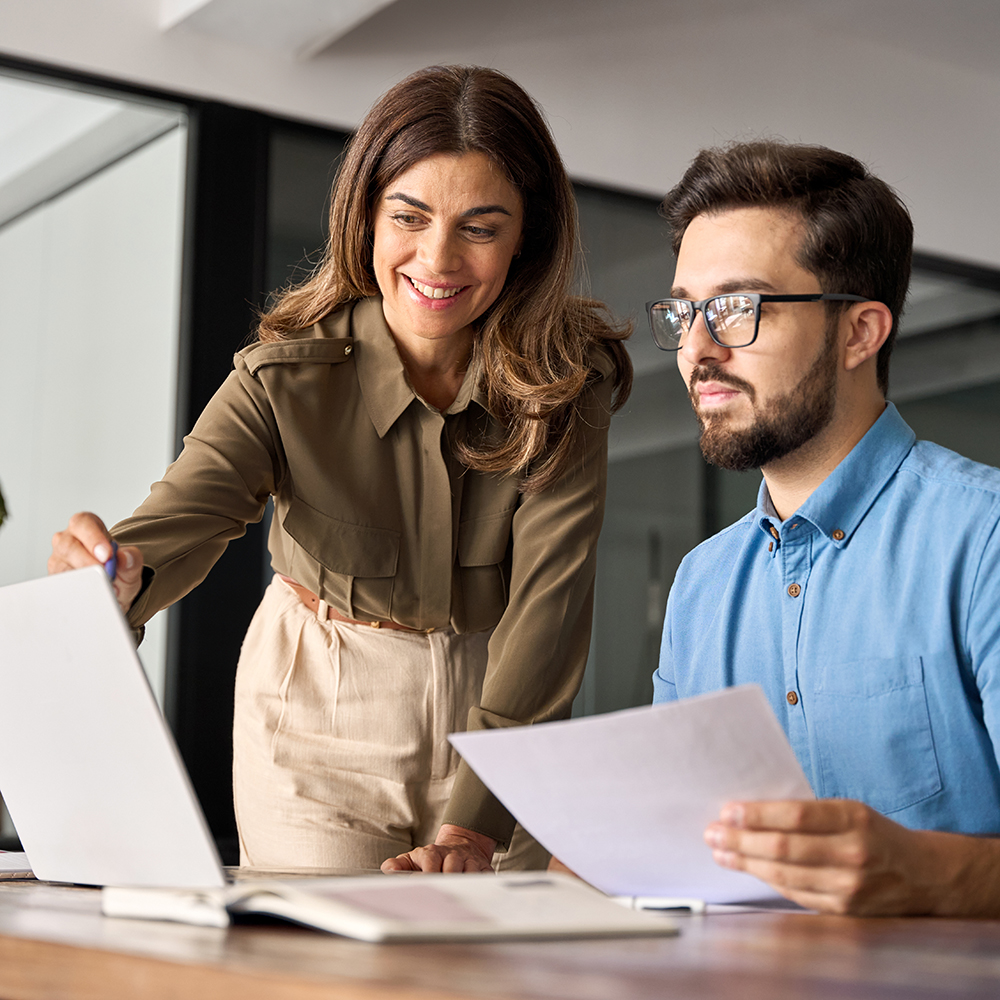 Professional happy manager explaining software helping employee at work.
